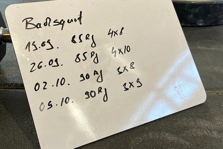 Whiteboard mit handschriftlichen Trainingseinträgen für Backsquat in einer CrossFit-Box