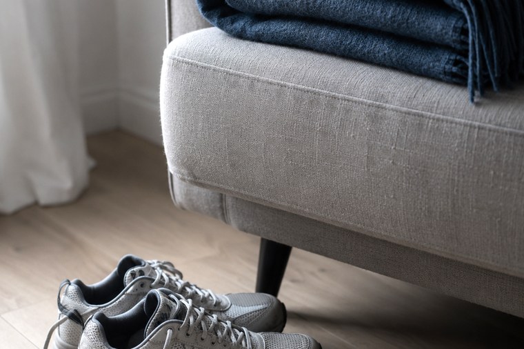 Zusammengelegte Decke auf einem Sessel mit Laufschuhen davor